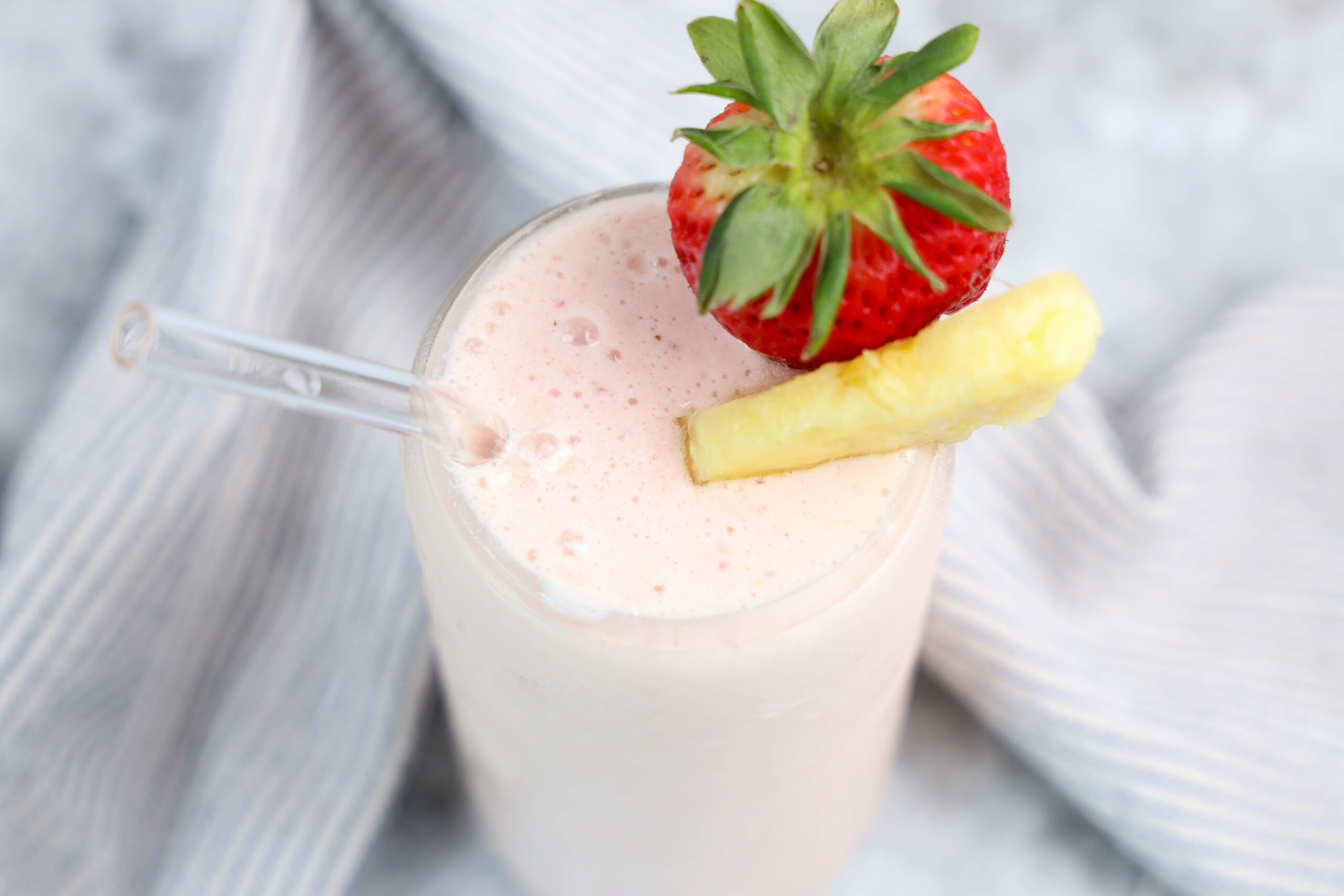 Overhead view of tropical fruit smoothie topped with pineapple and strawberry.