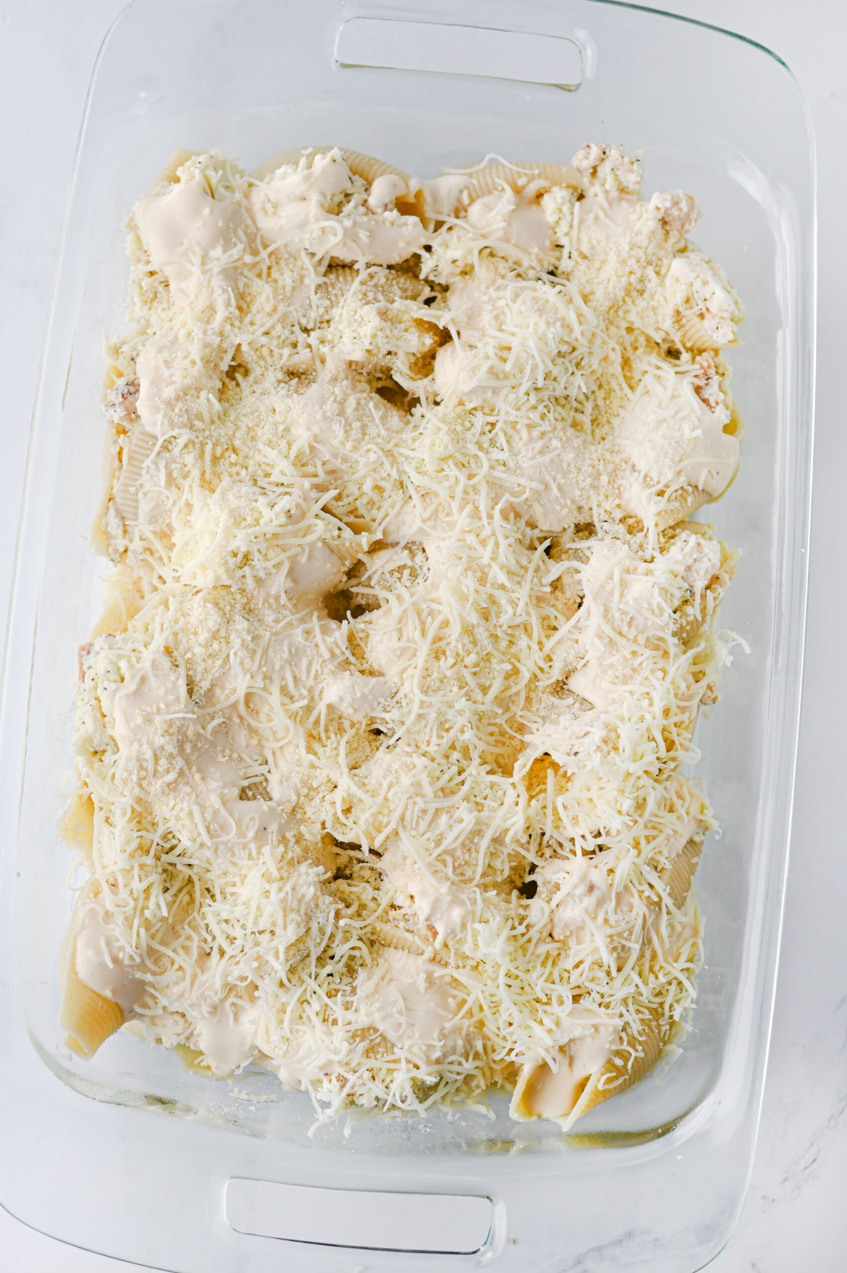 Stuffed shells topped with mozzarella and parmesan before baking.