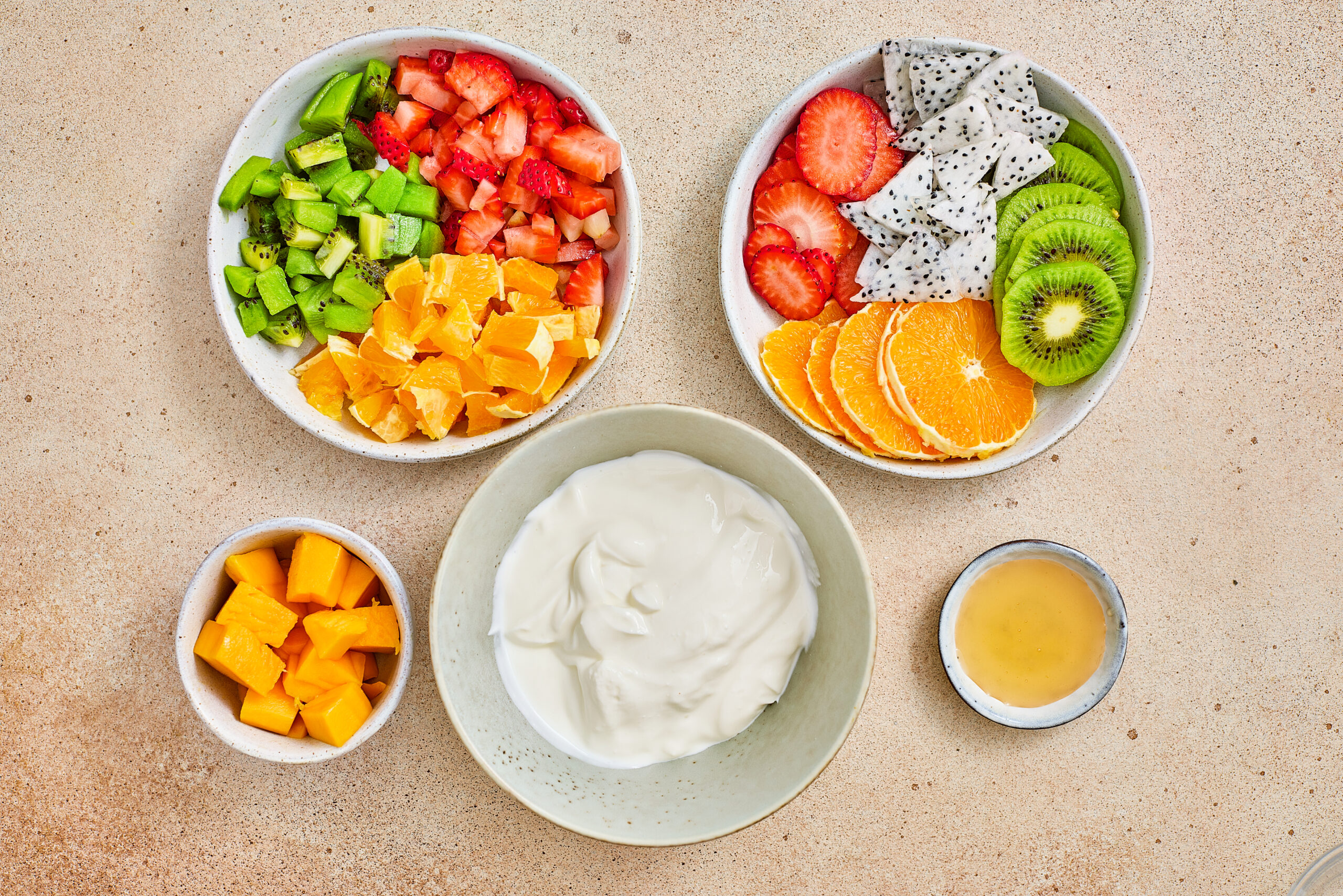 Greek yogurt, honey, mango, strawberries, kiwi, orange, and dragon fruit for tropical parfait cups.