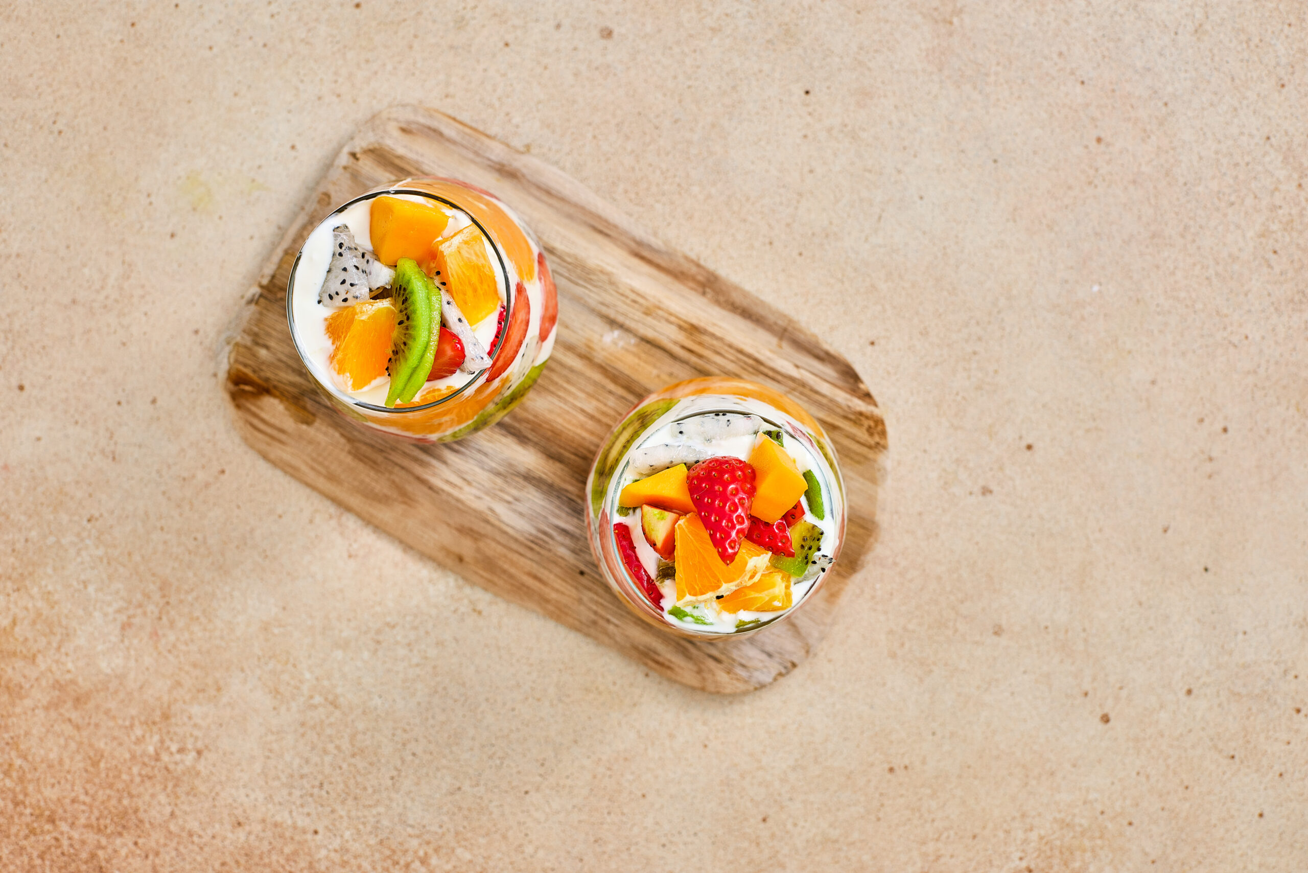Two tropical fruit parfait cups topped with fresh fruit.