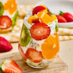 A tropical fruit parfait cup layered with Greek yogurt, mango, strawberries, kiwi, orange, and dragon fruit.