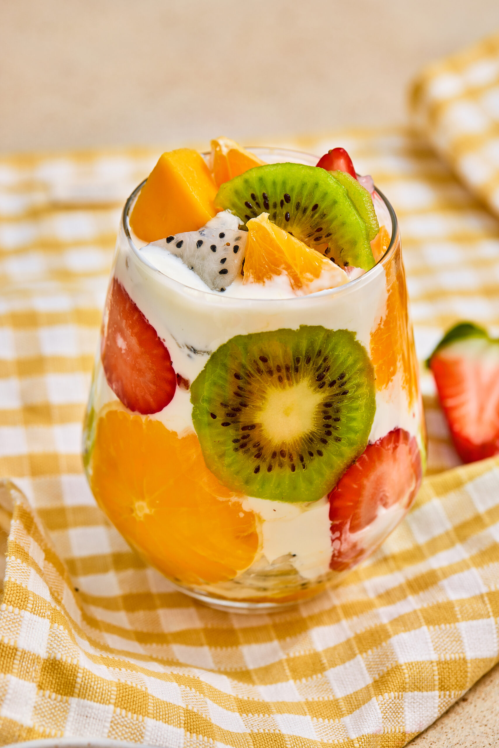 Closeup of a tropical fruit parfait cup with yogurt and colorful fresh fruit.
