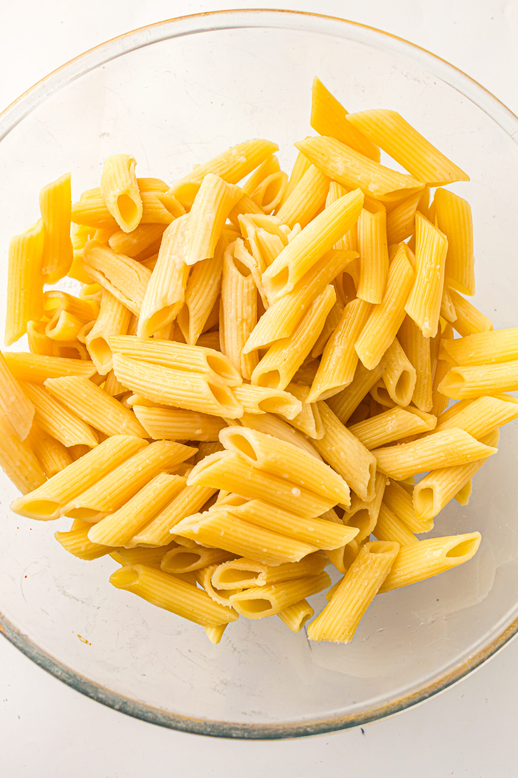 Al dente tube pasta drained into a glass mixing bowl.