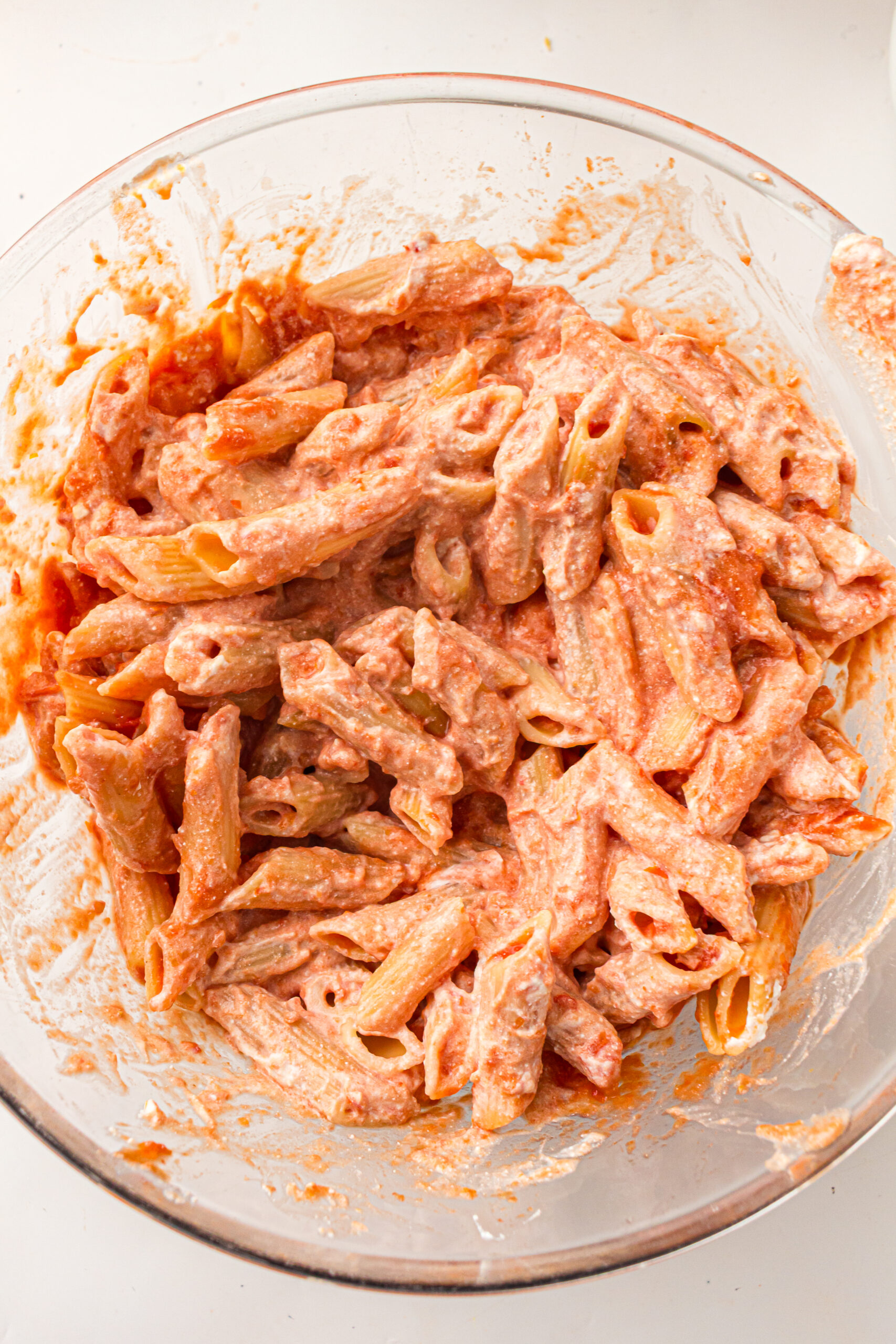 Cooked pasta evenly coated with marinara sauce and ricotta.