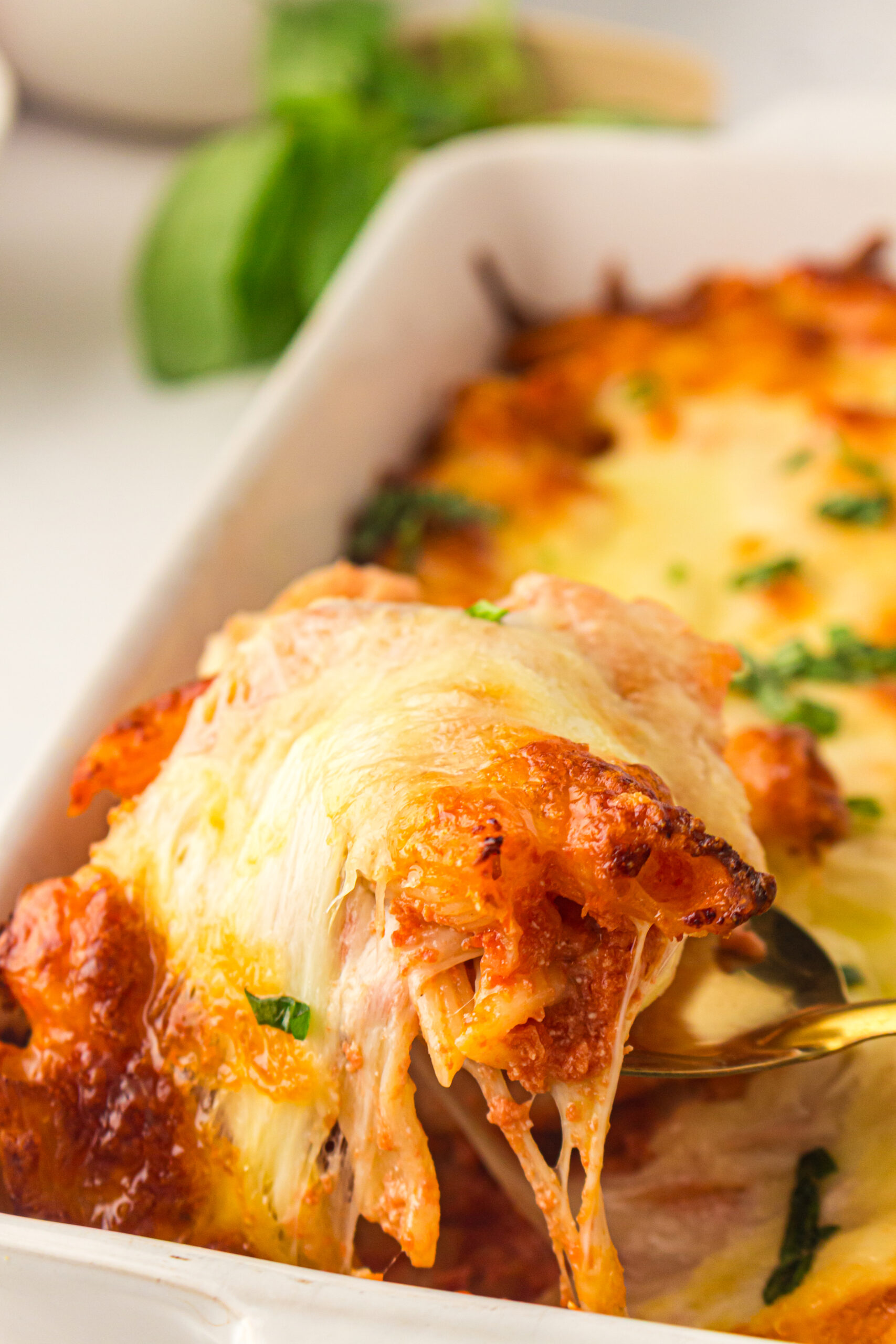 A spoonful of baked ziti lifted from the casserole with melted mozzarella.