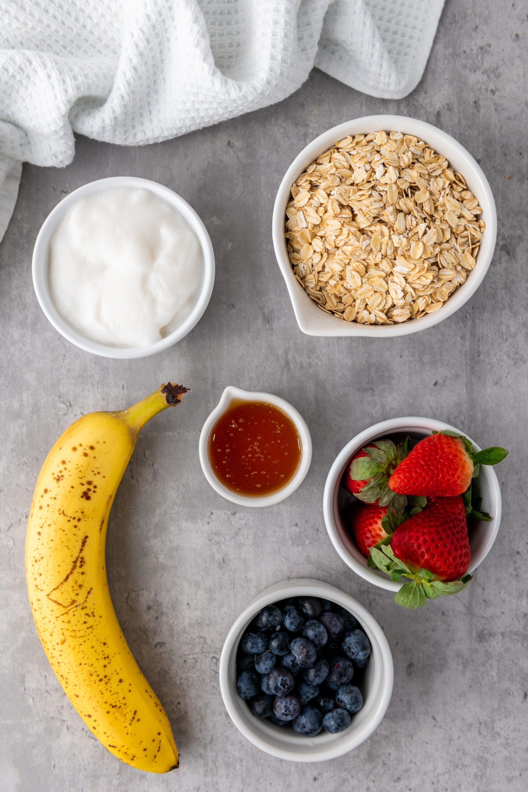 Rolled oats, ripe banana, honey, yogurt, strawberries, and blueberries for granola cups.