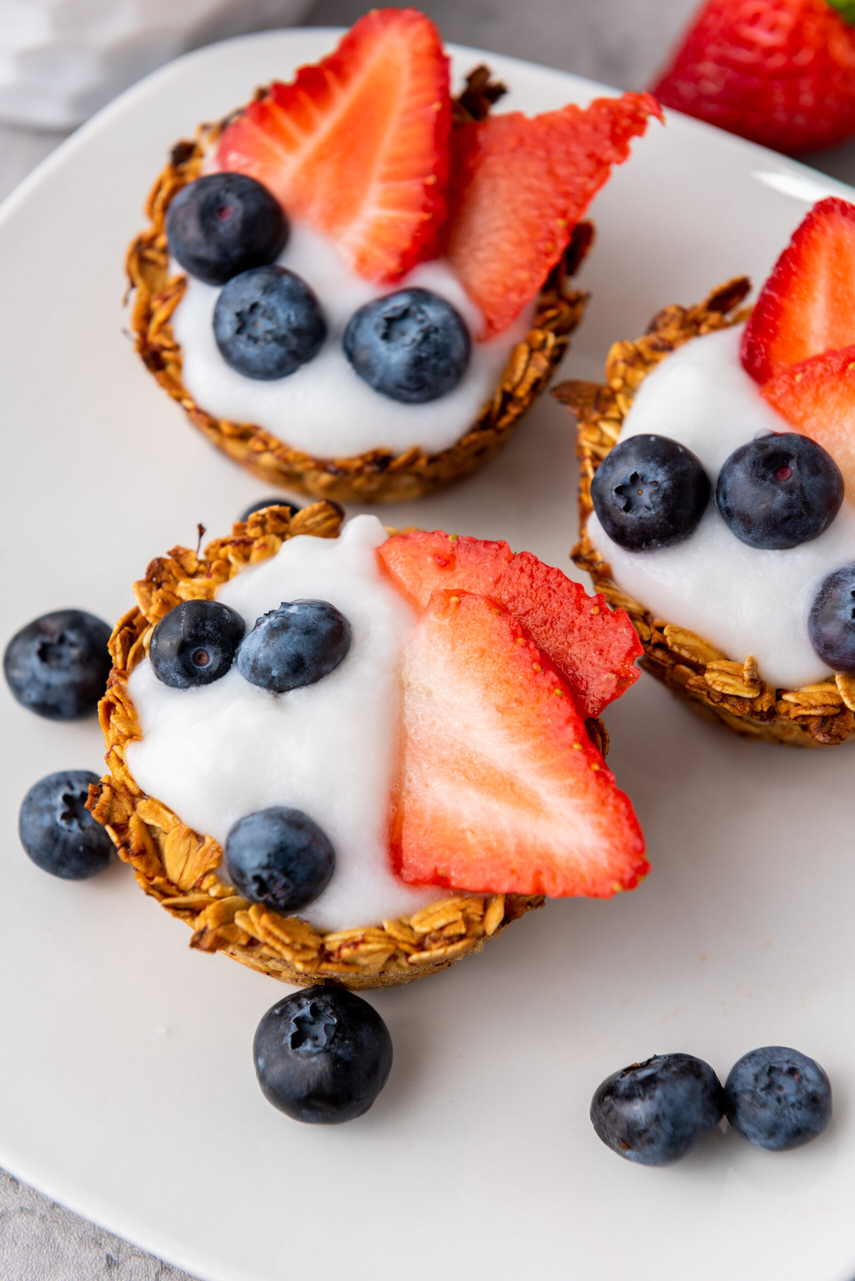Closeup of chewy granola cups filled with yogurt, strawberries, and blueberries.