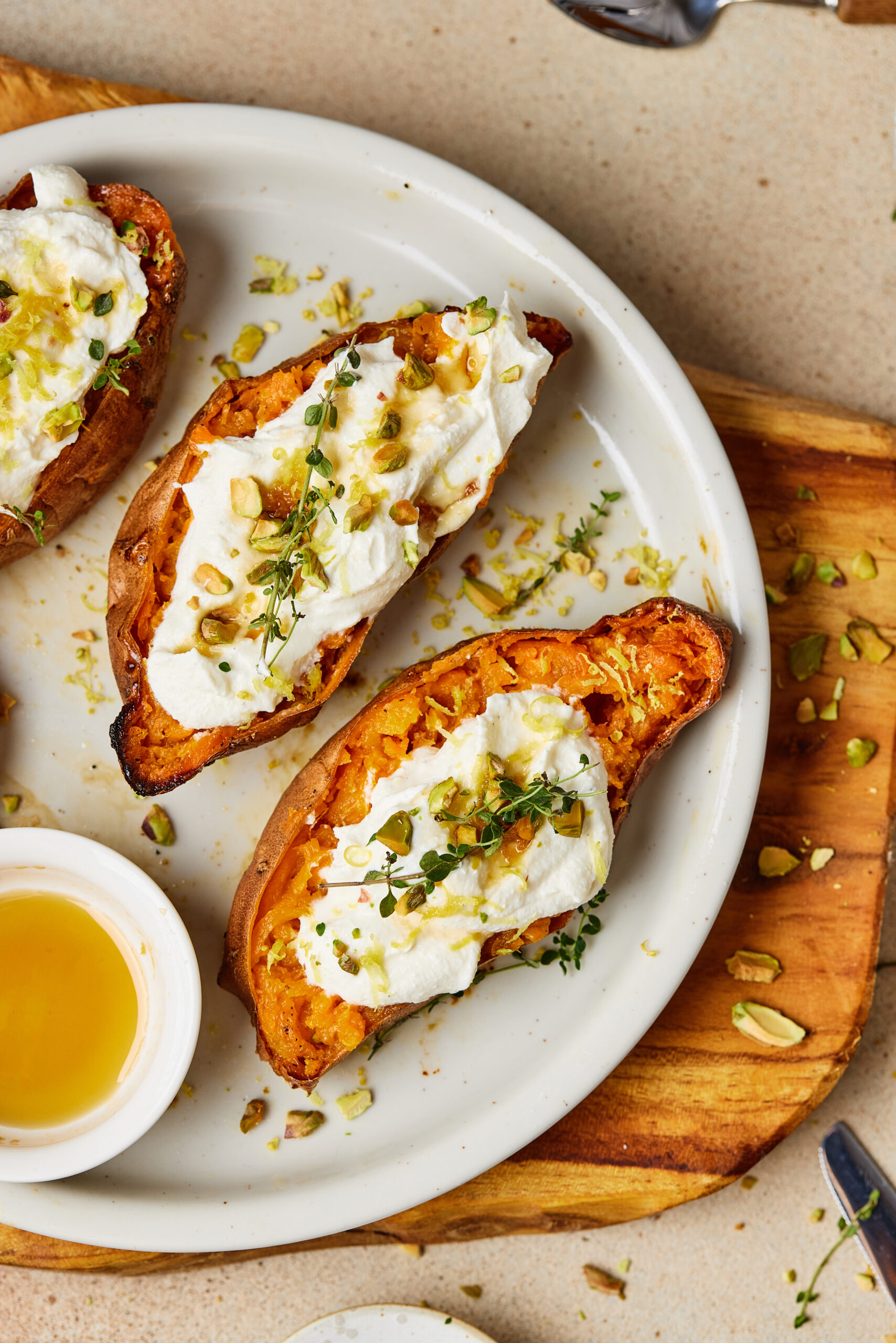 Close-up of roasted sweet potatoes with creamy ricotta, pistachios, lemon zest, thyme, and honey.