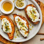 Roasted sweet potato halves topped with whipped ricotta, pistachios, lemon zest, thyme, and honey.