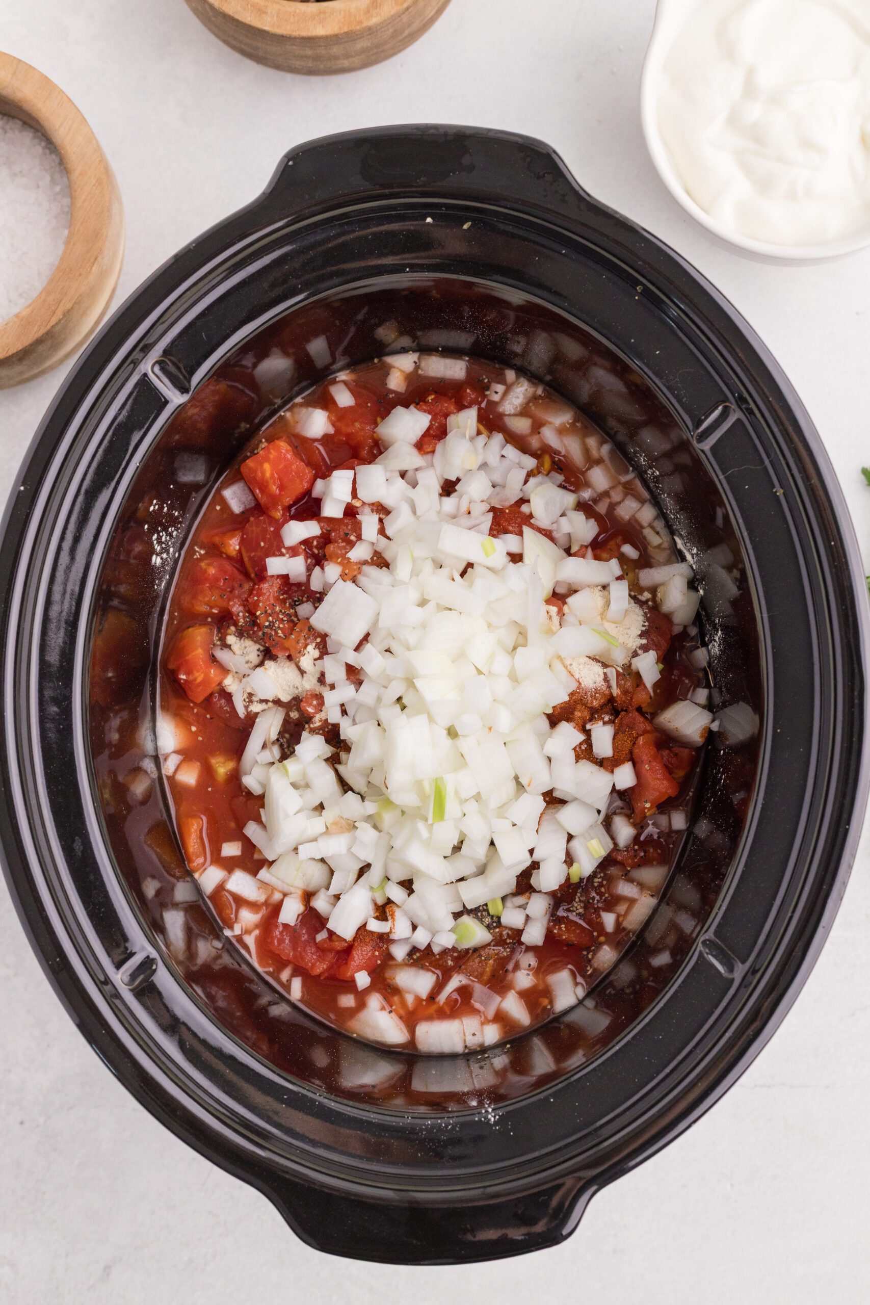 Chicken paprikash ingredients added to a slow cooker before stirring.
