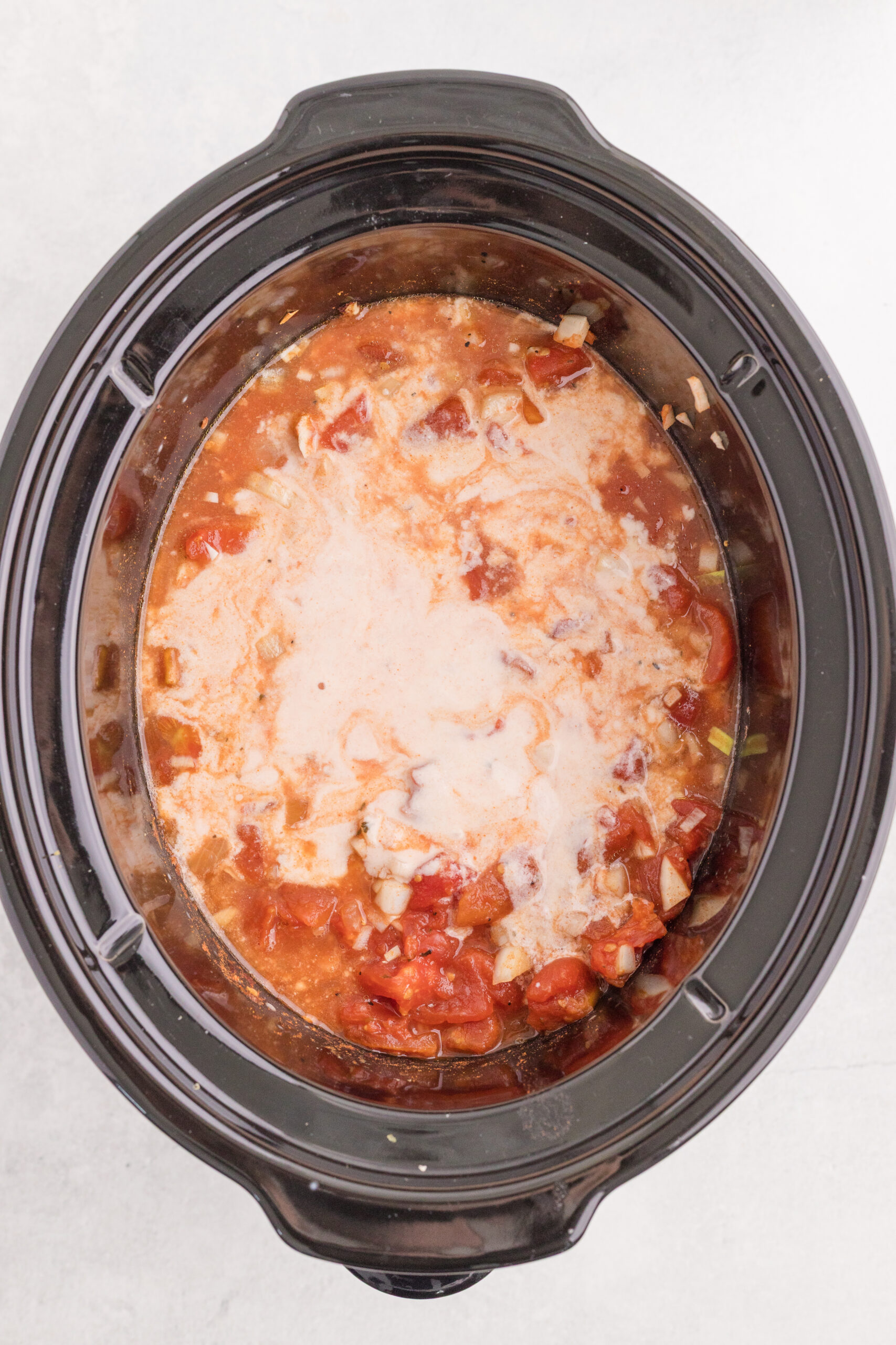 Tempered sour cream mixture added to cooked chicken paprikash in the slow cooker.