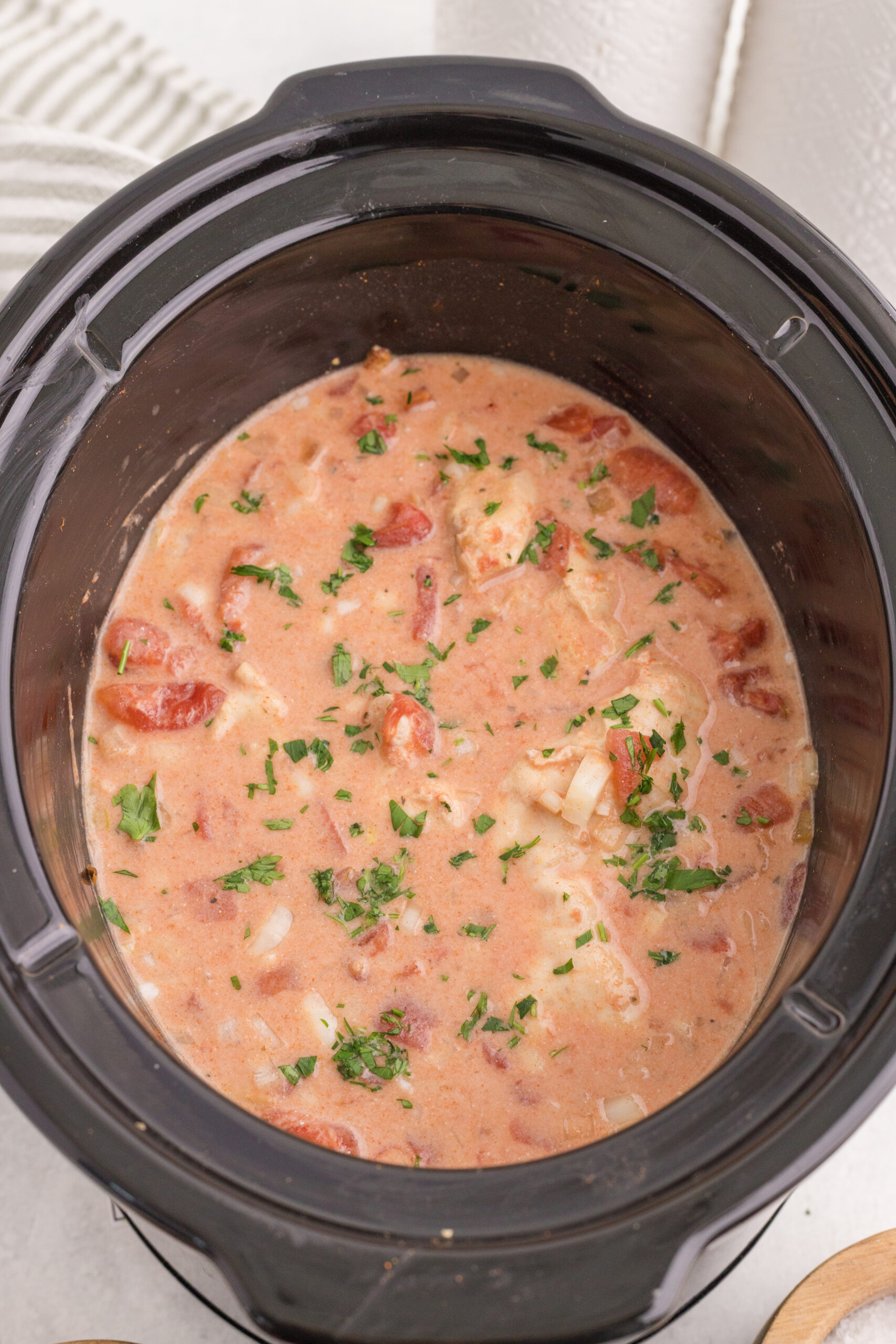 Creamy chicken paprikash finished with chopped parsley in the slow cooker.