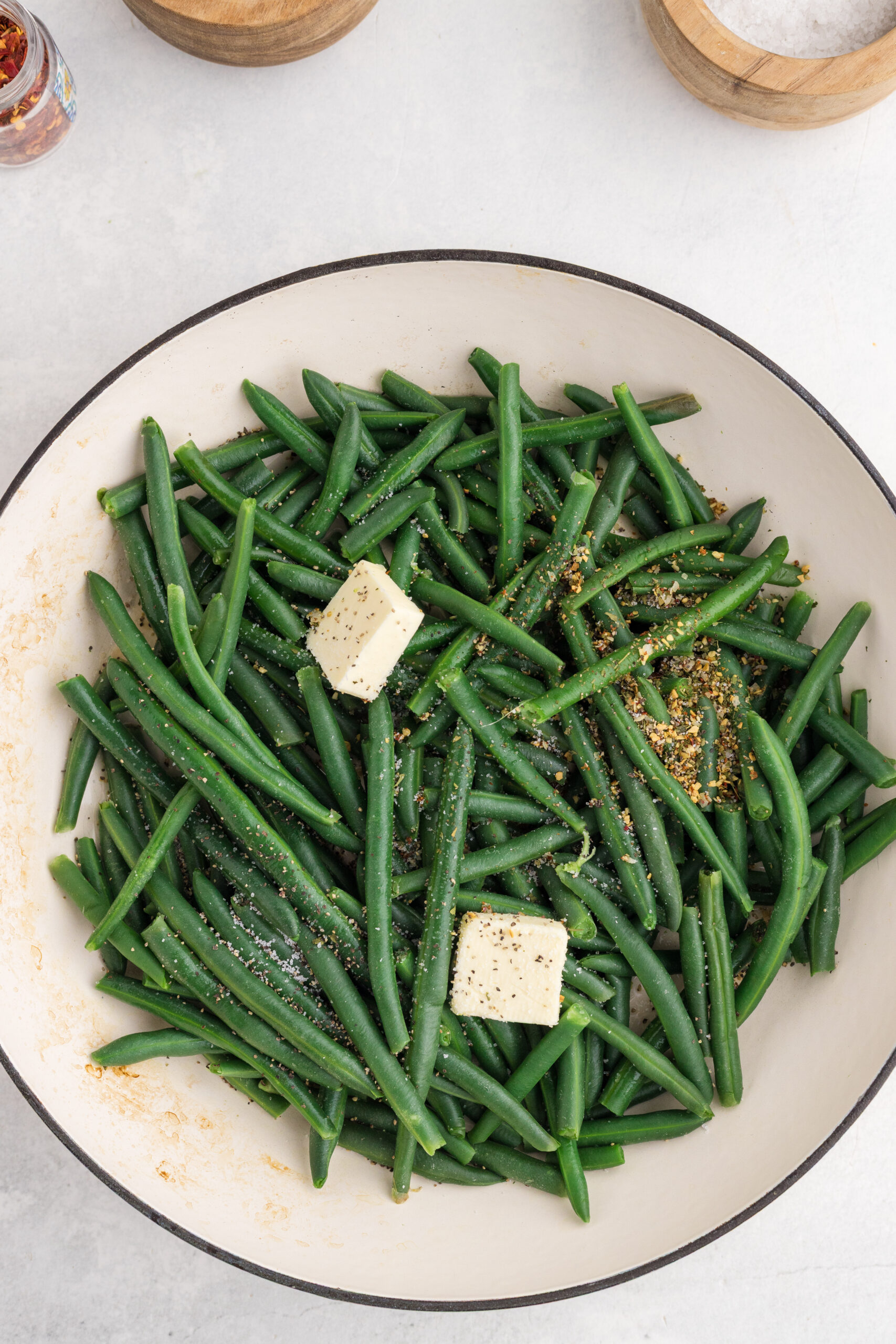 Butter and Italian seasoning added to drained green beans in a skillet.