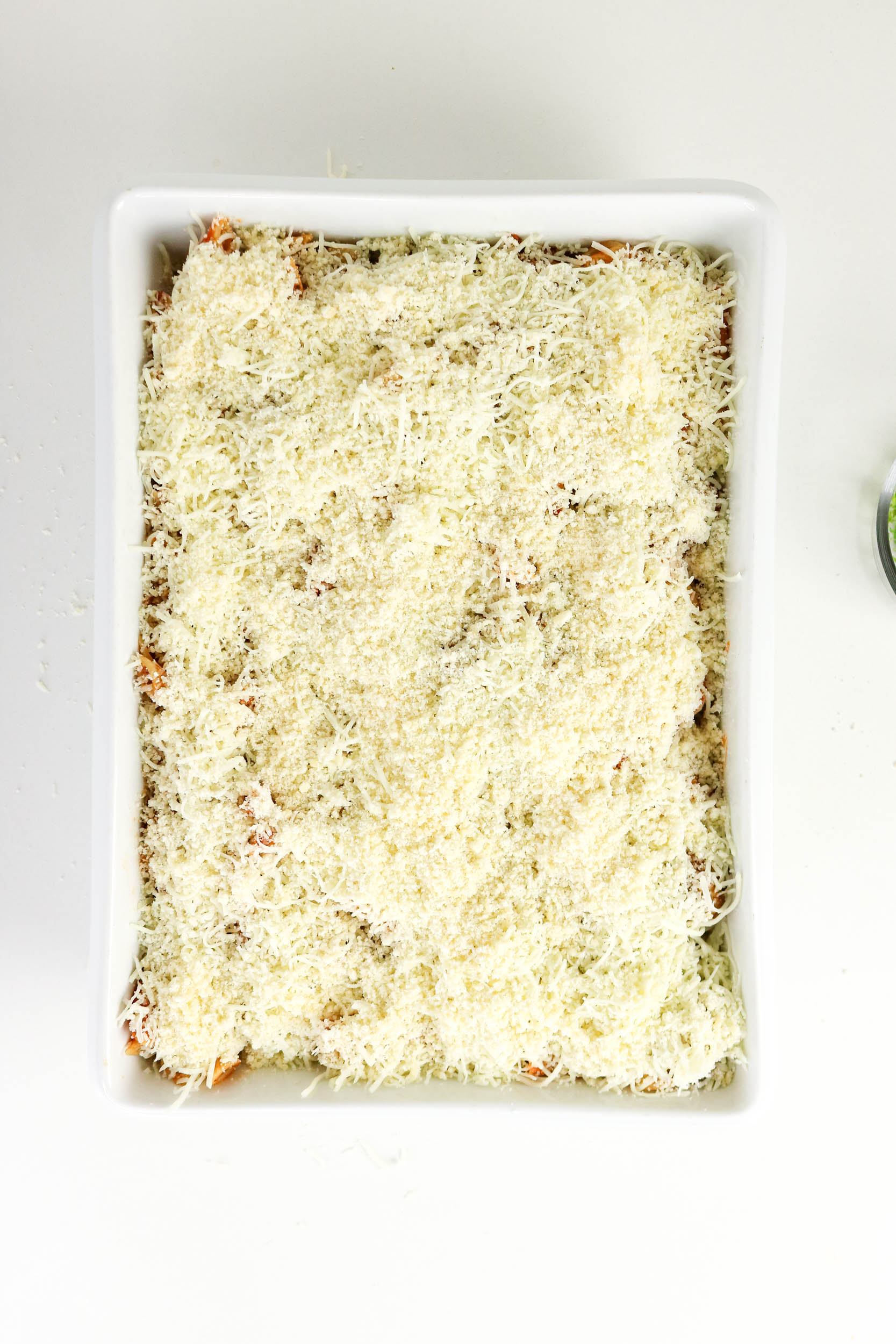 Unbaked meatball casserole topped with mozzarella and Parmesan