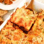 Cheesy meatball casserole being served with a wooden spoon.