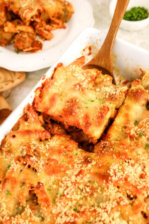 Cheesy meatball casserole being served with a wooden spoon.