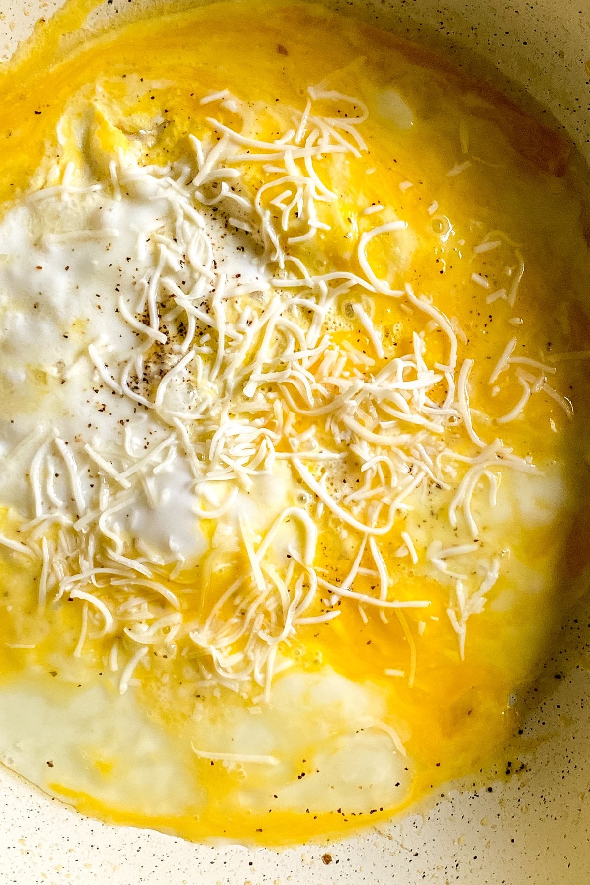 shredded cheese over eggs for an egg and cheese quesadilla