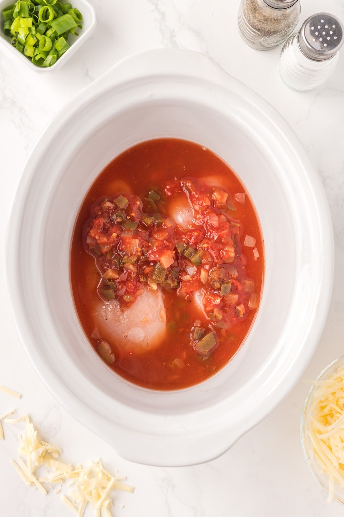 chicken breasts covered in salsa in a slow cooker