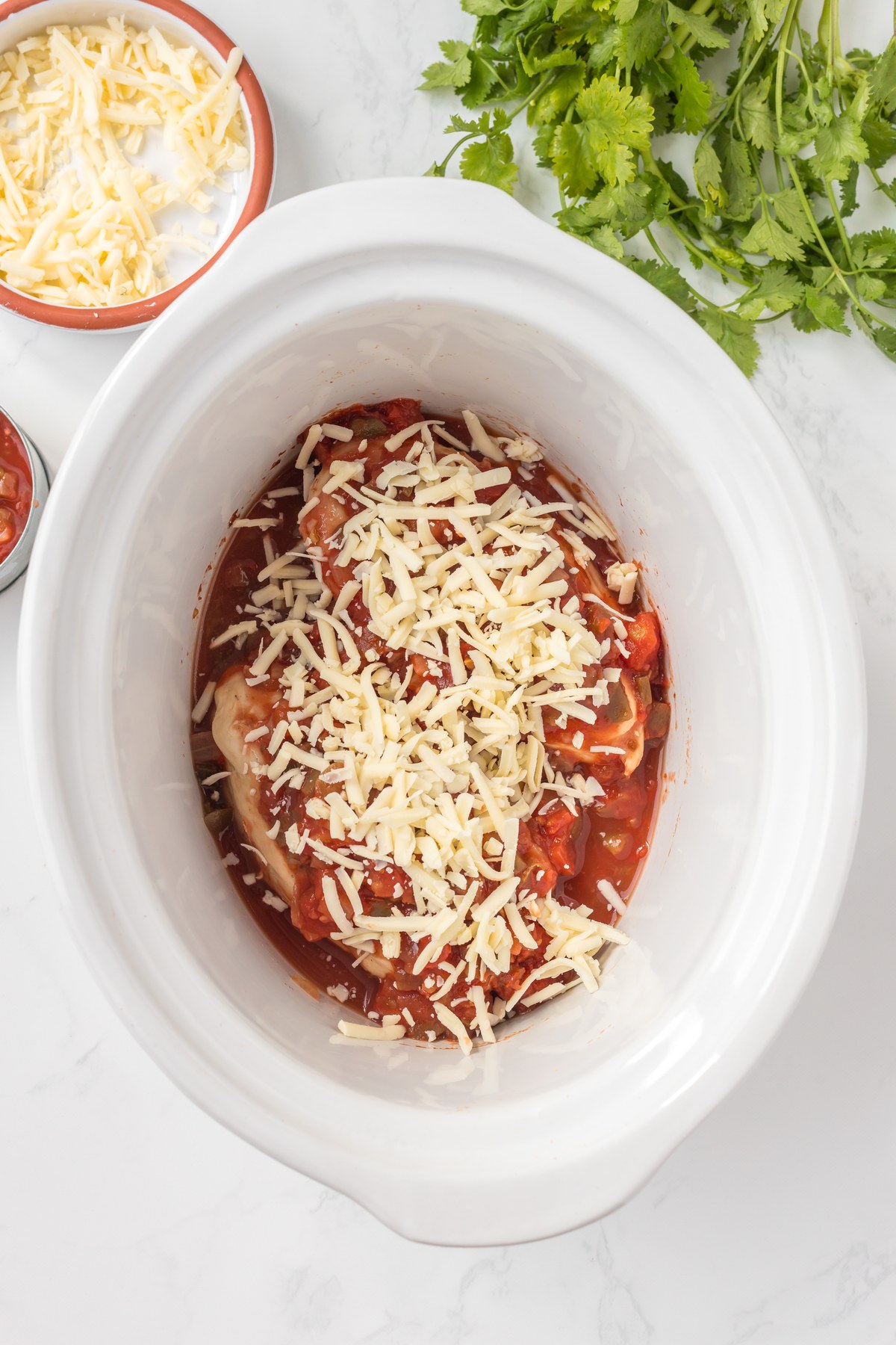 Monterey Jack sprinkled over salsa chicken in the slow cooker