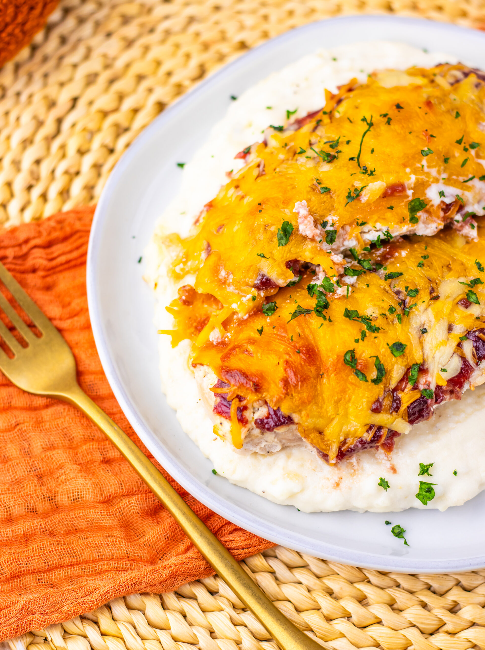 Plated cranberry cream cheese chicken bake over mashed potatoes.