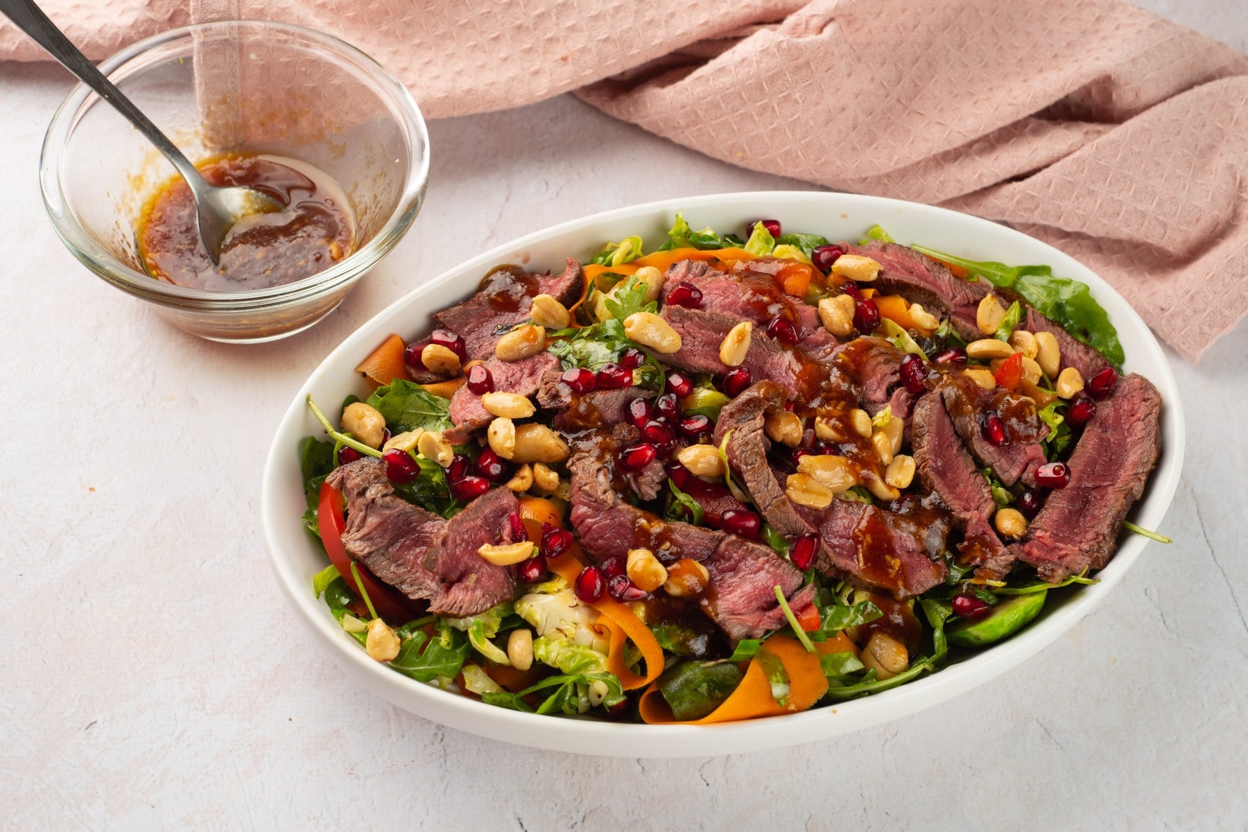 Finished winter steak salad with Brussels sprouts and pomegranate, with dressing on the side.