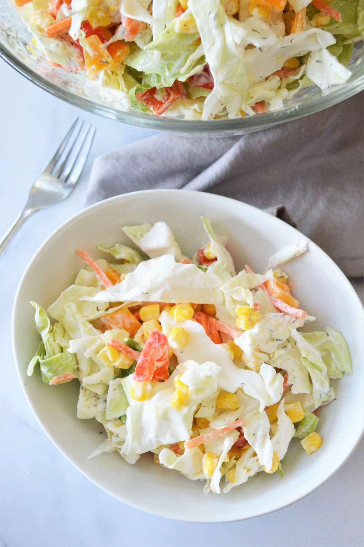 overhead bowl of no mayo coleslaw with corn, carrots and peppers next to a fork