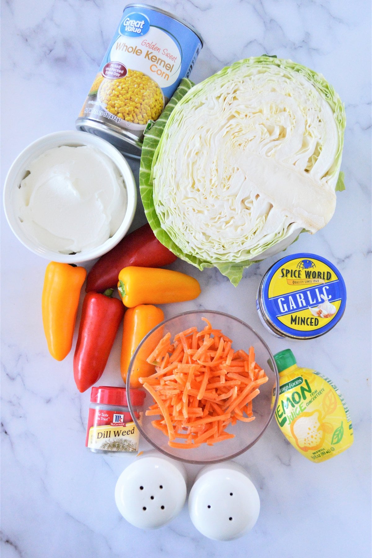 ingredients for Greek yogurt coleslaw: green cabbage, shredded carrots, mini sweet peppers, canned corn, Greek yogurt, garlic, lemon juice, dill, salt and pepper