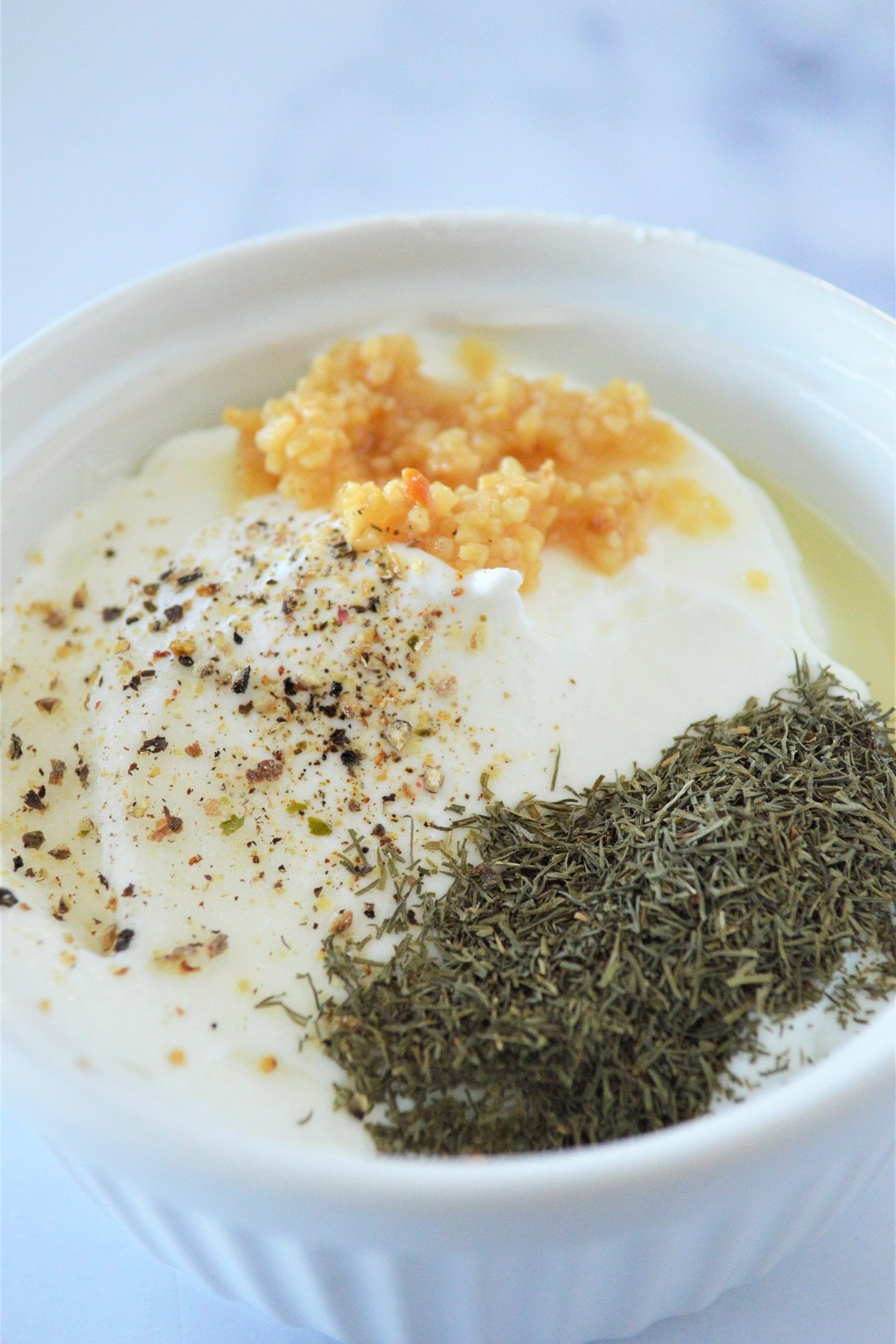 Greek yogurt with minced garlic, dill and black pepper in a small bowl