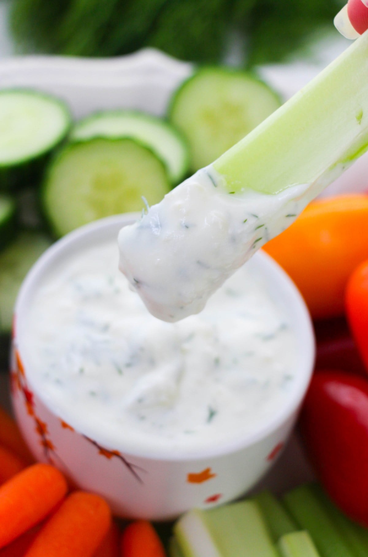 celery stick scooping dill veggie dip from a bowl