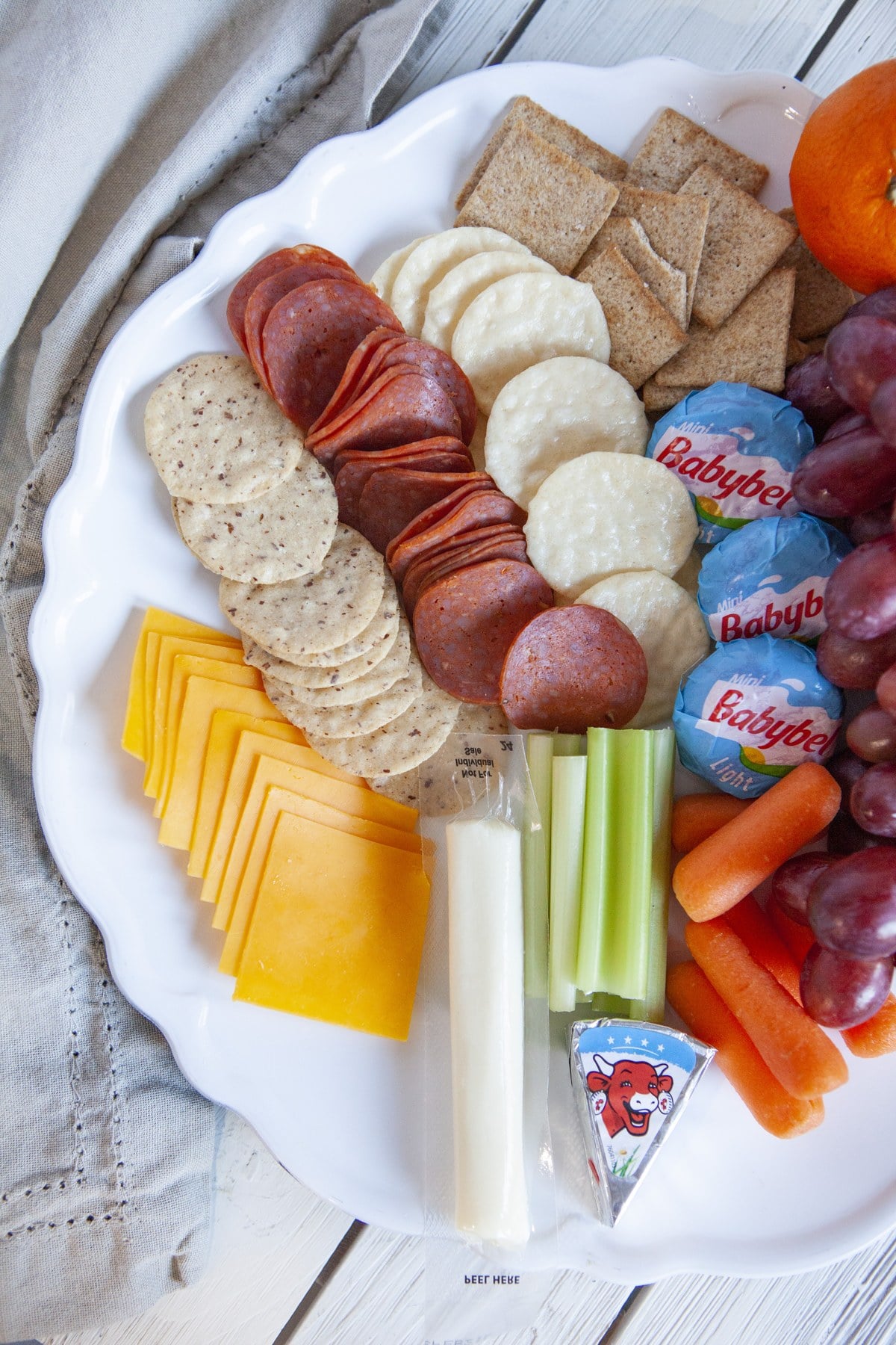 Healthy charcuterie board with grapes, crackers, and light cheeses, viewed from above.