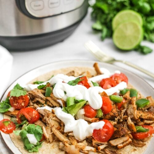 Pork carnitas on a tortilla with toppings, with the Instant Pot behind.