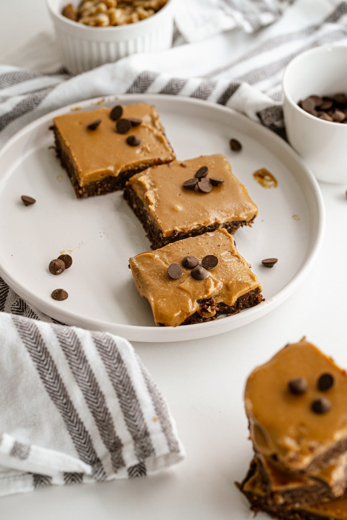 Plated no-bake date brownie squares with peanut butter caramel and chocolate chips.