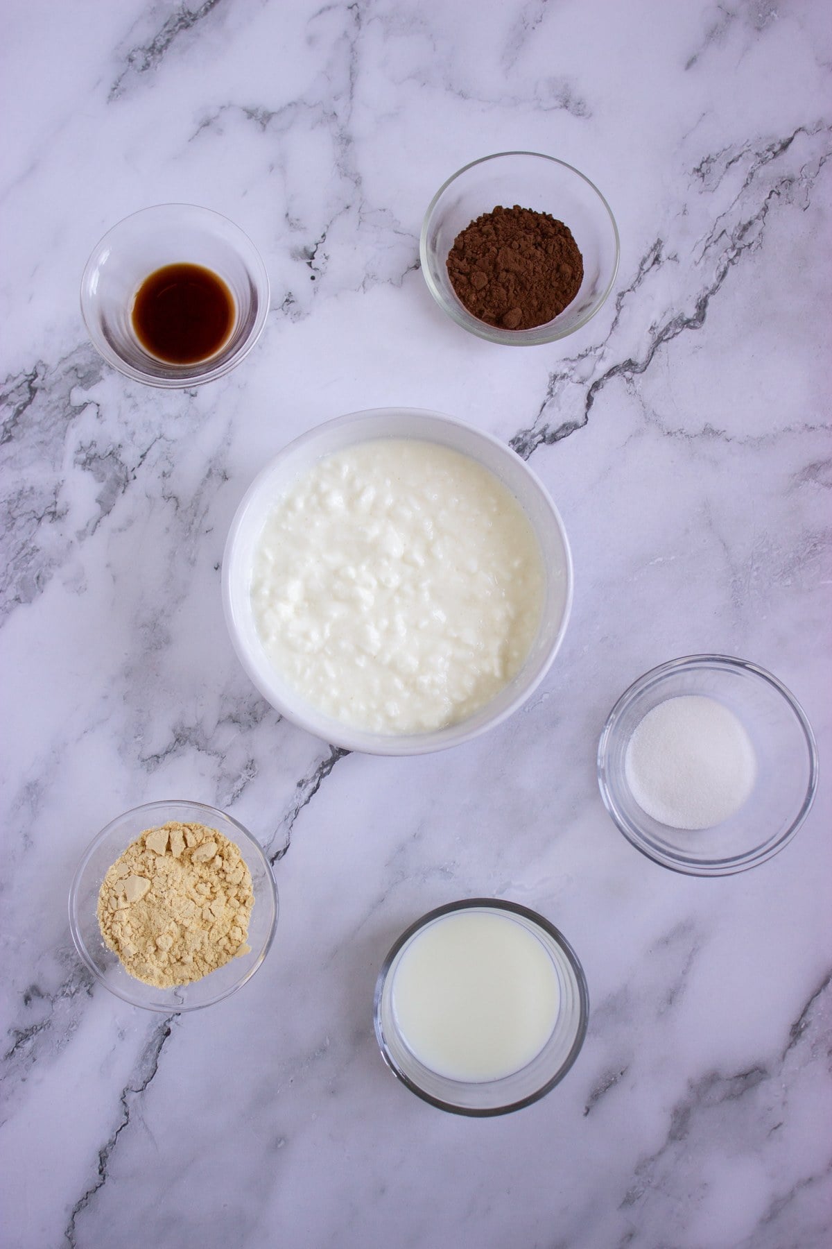 Ingredients in bowls for chocolate peanut butter cottage cheese pudding, viewed from above.