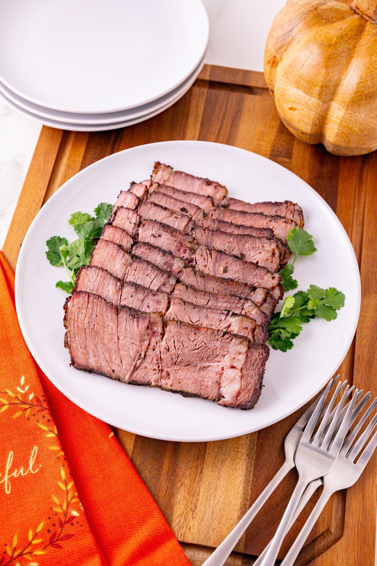 sliced reverse sear chuck roast on a white platter with a fall table setting