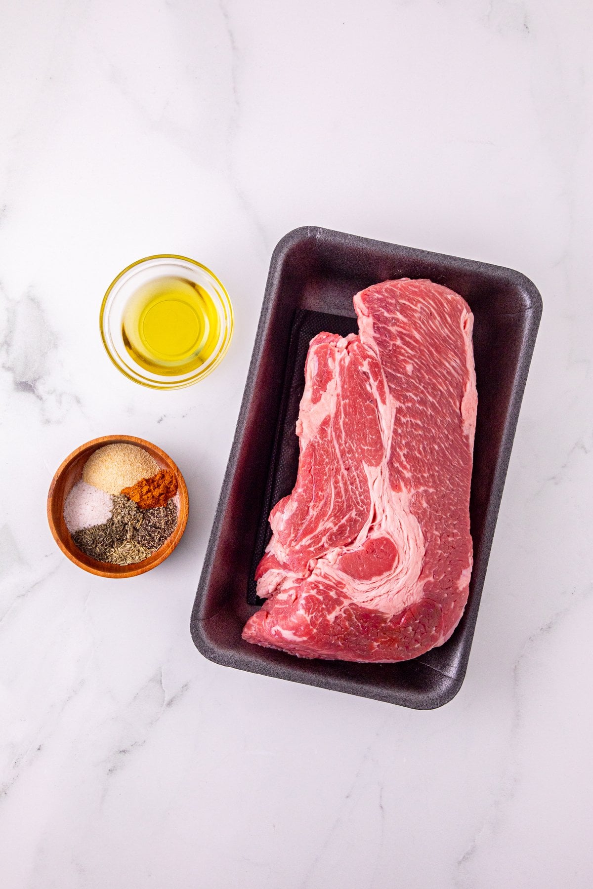 raw boneless chuck roast with salt, garlic powder, pepper, herbs and oil for a reverse sear chuck roast