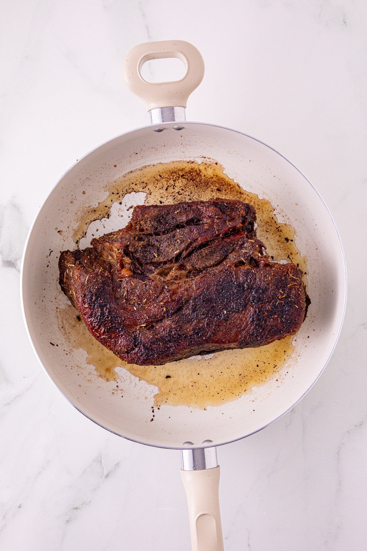 searing the chuck roast in a hot skillet for a dark crust