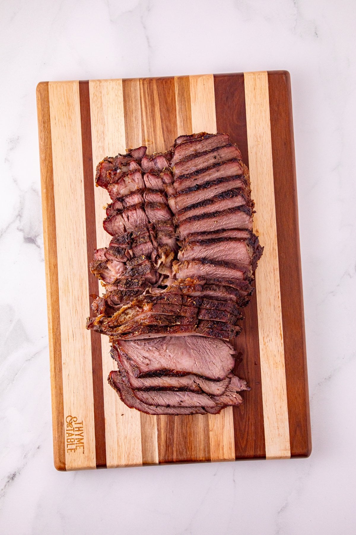 reverse seared chuck roast sliced thin against the grain on a cutting board
