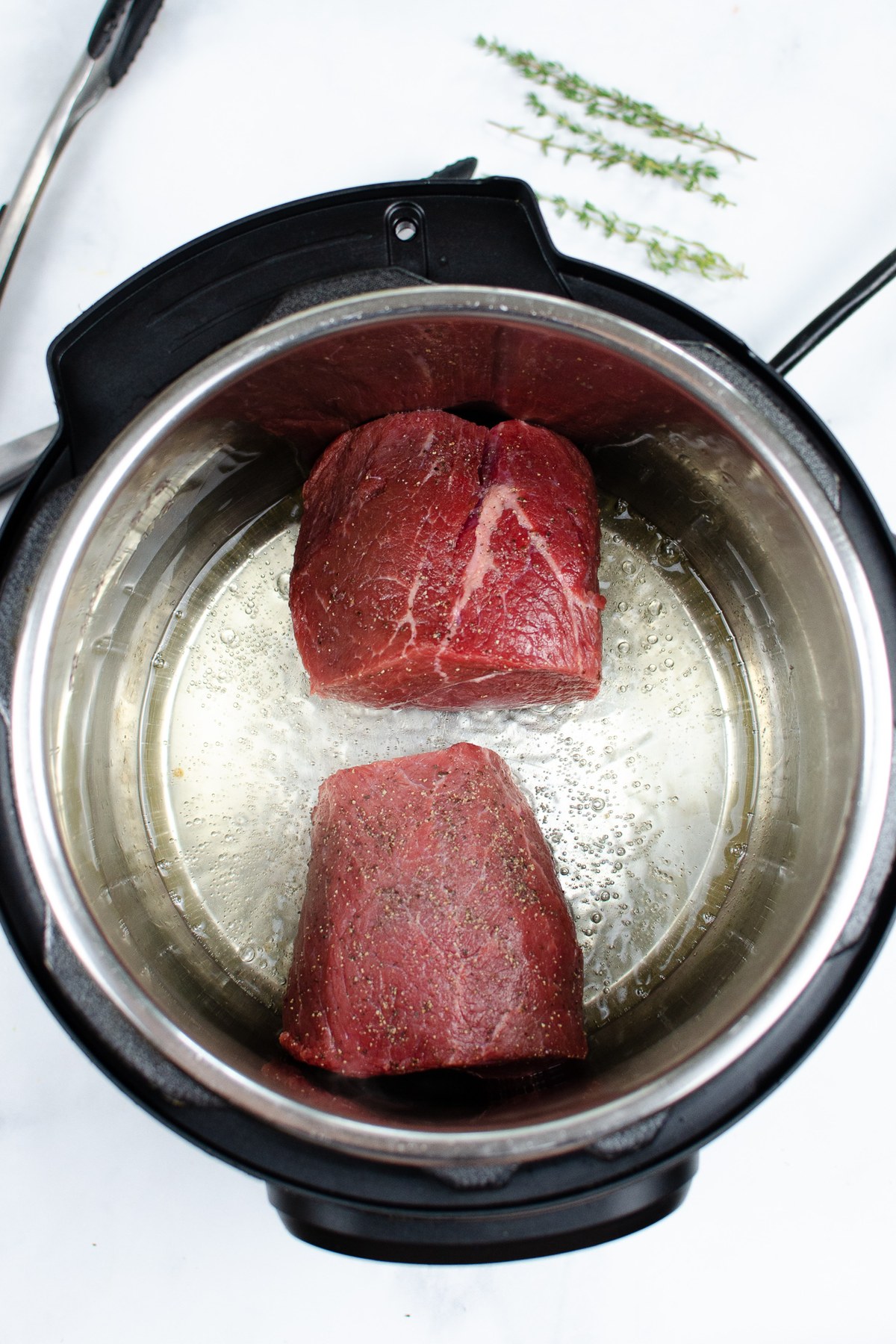 Sear both halves of the seasoned roast on all sides, then set them aside.