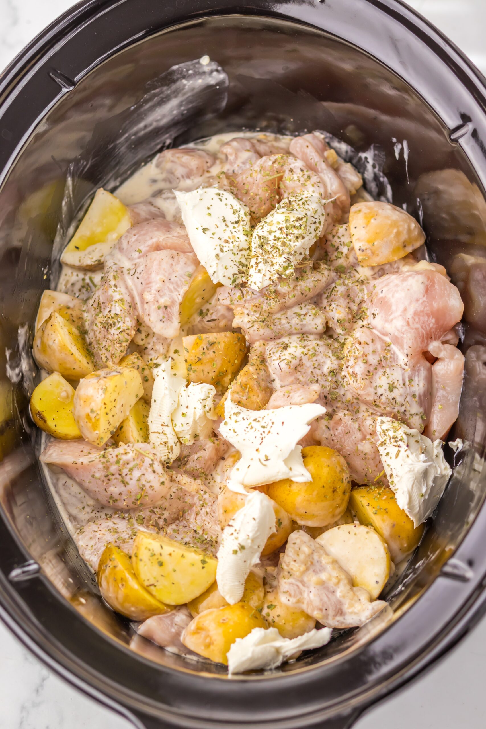 Cubed cream cheese and Italian seasoning added to the slow cooker.