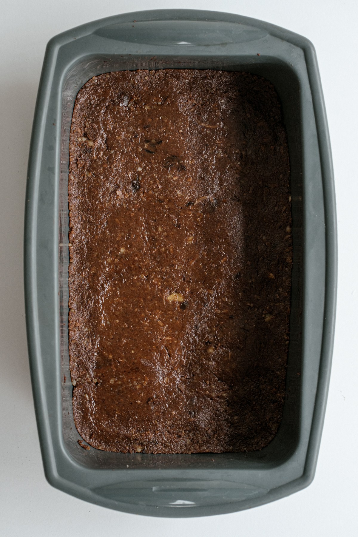 Brownie dough pressed into a lined loaf pan.