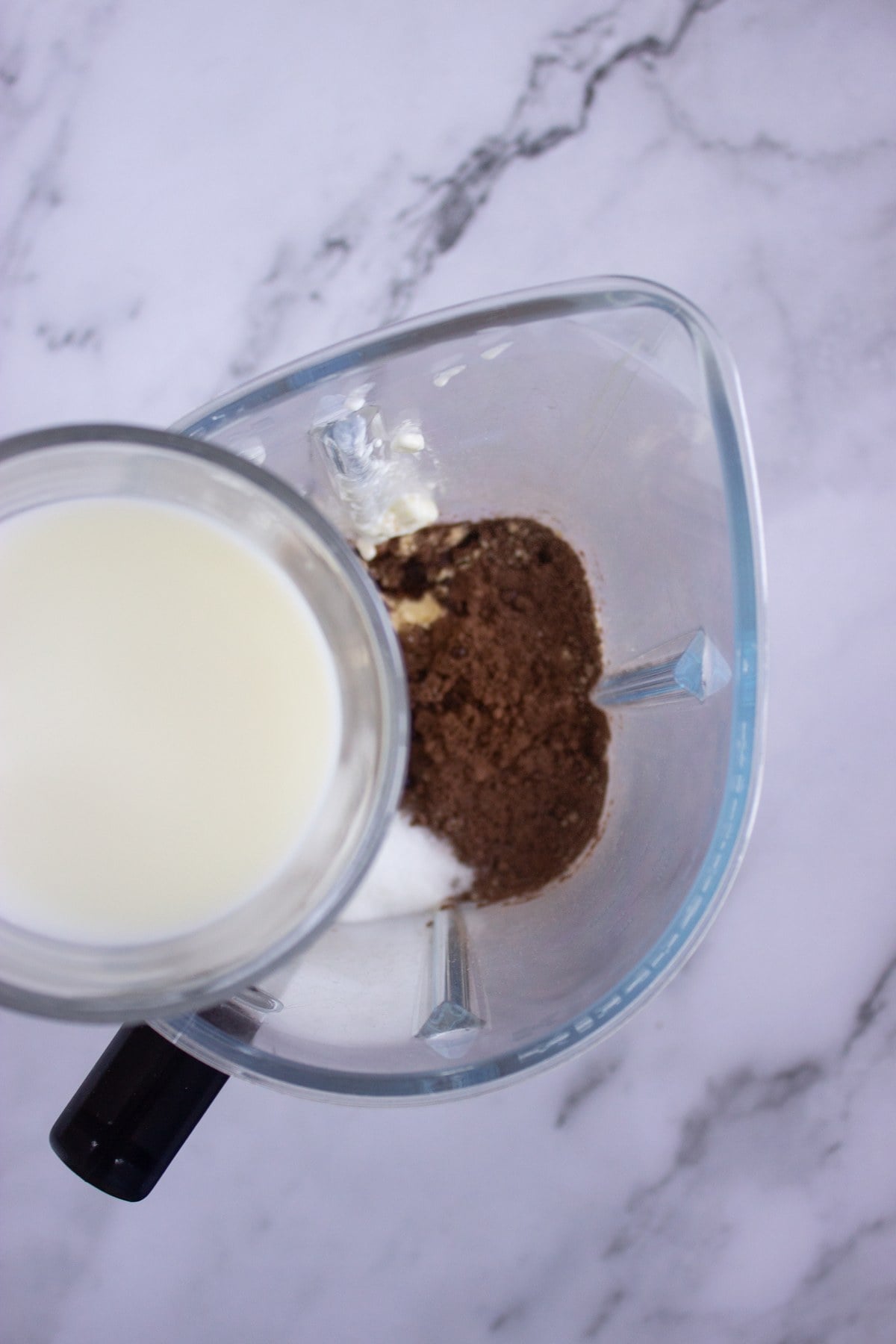Almond milk poured into the blender with the vanilla and sweetener already added.