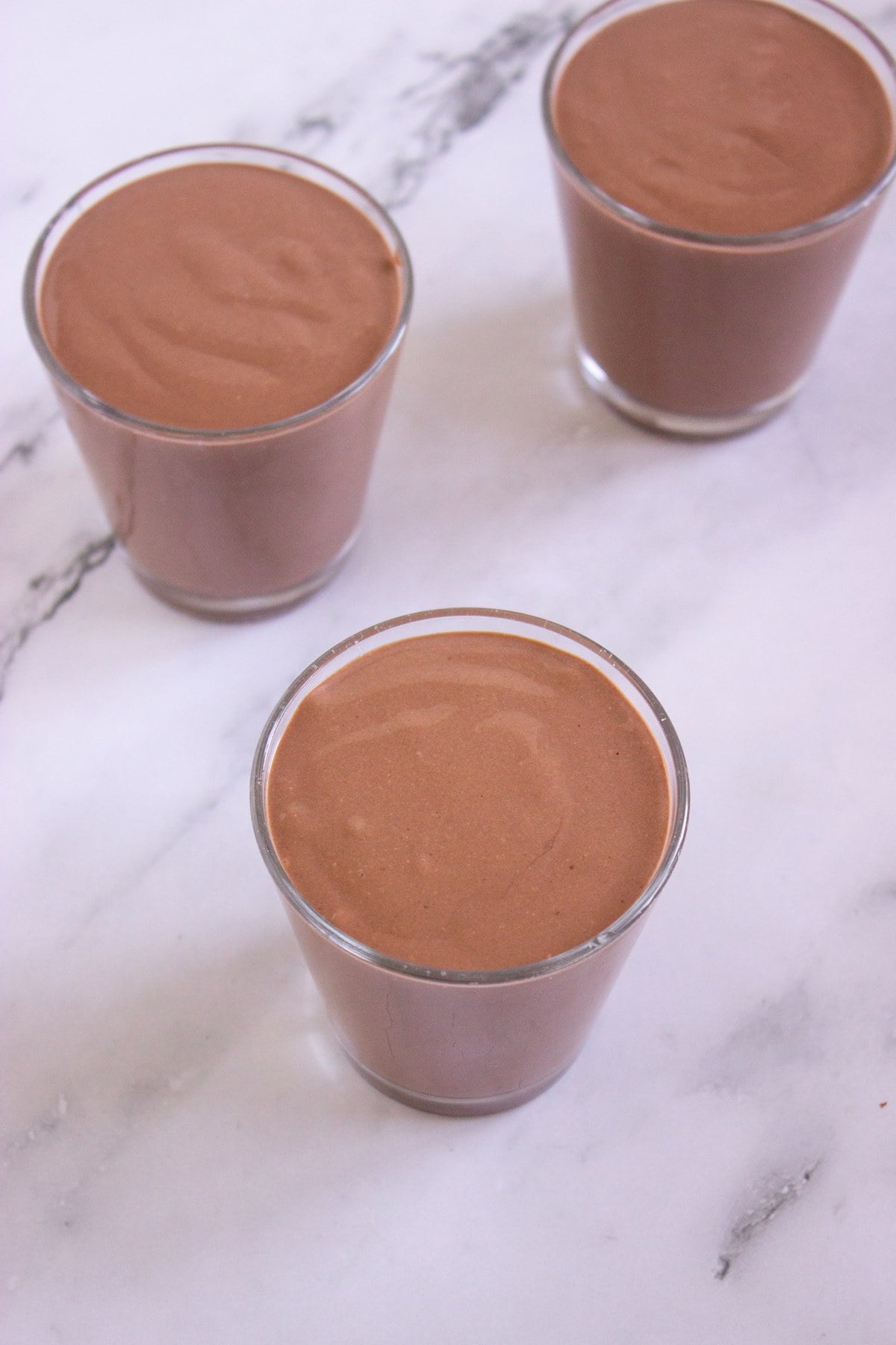 Chocolate peanut butter cottage cheese pudding portioned into glasses.